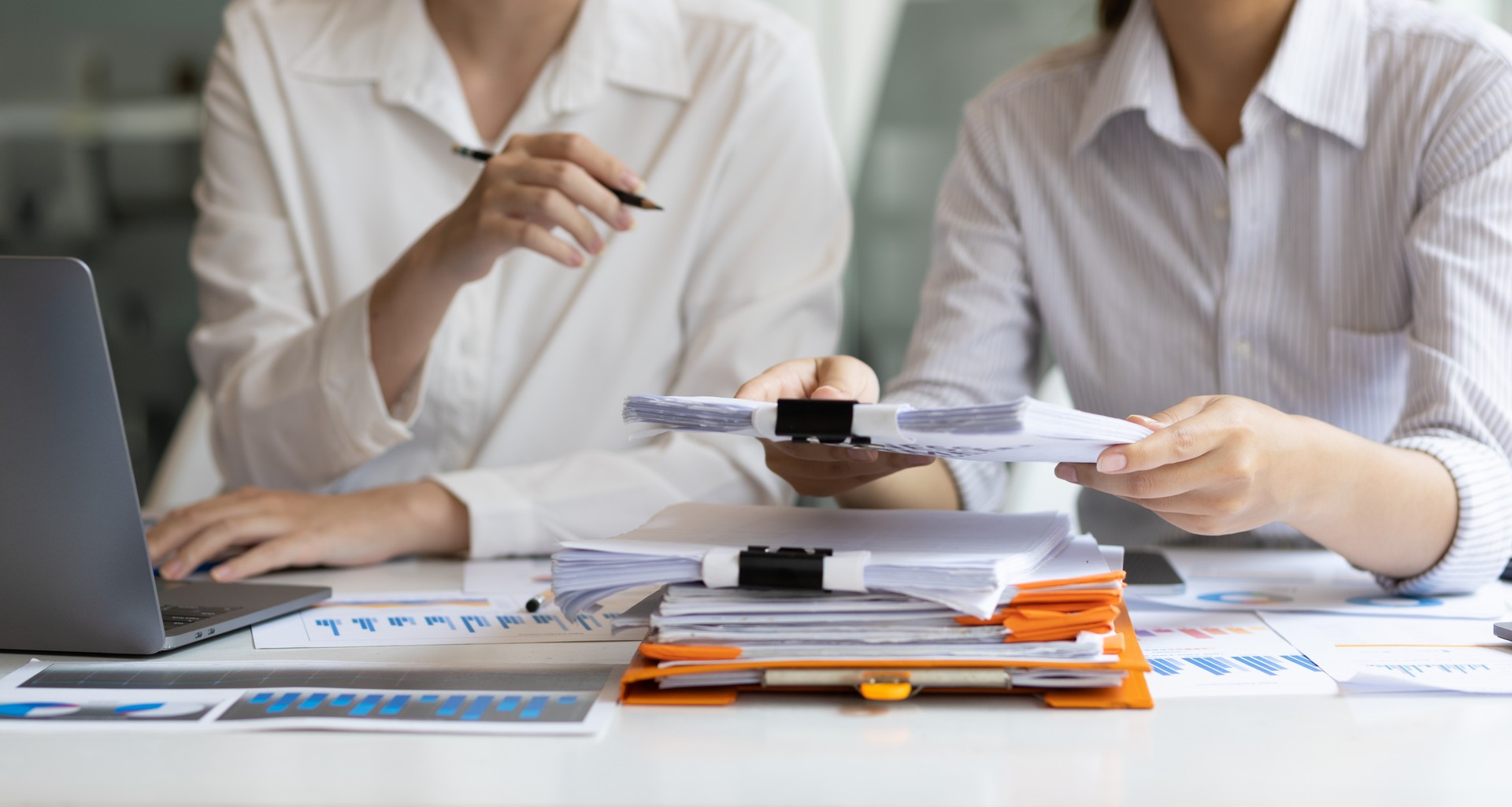 Colleagues work on paperwork on their desks. Businesswoman discussing business project project documents in office.